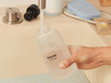 A person filling a Blueland hand soap bottle with water, adding a tablet, then washing their hands with foaming soap