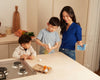 A mom and her two young boys cleaning their kitchen counter with multi-surface cleaner