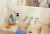 A bathroom sink with eco-friendly products like blueland hand soap, bamboo comb and toothbrush
