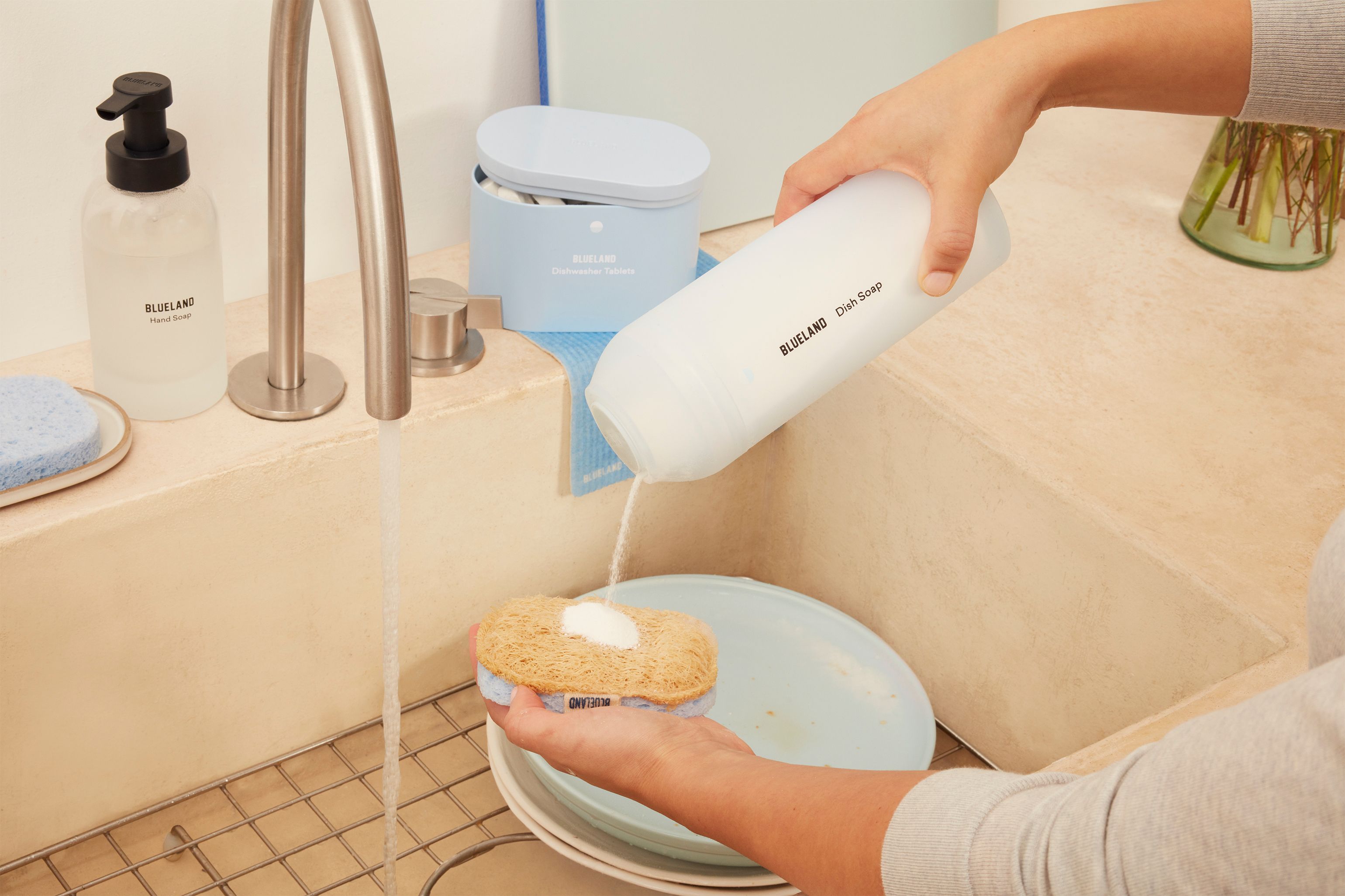 Person using a Blueland bottle to Blueland dish soap onto a sponge