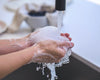 Hands holding soapy bubbles under running water