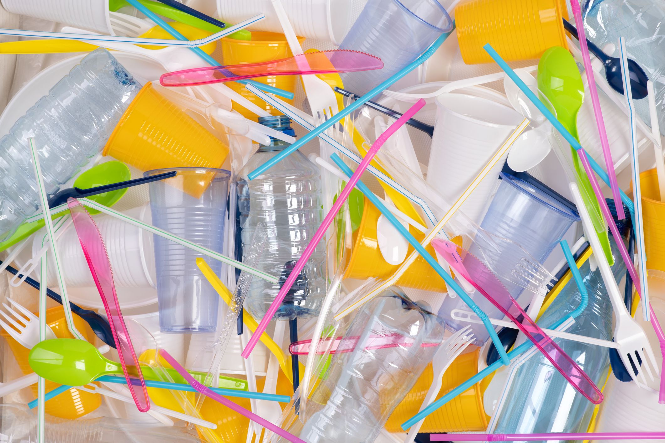 Assorted plastic straws and cups in various colors on a white background