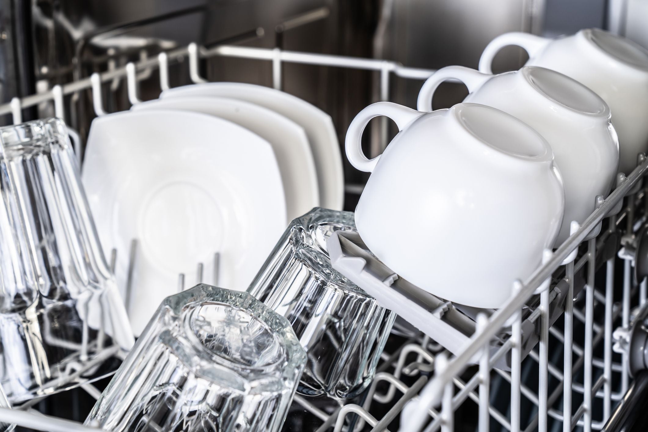Dishwasher with clean dishes including cups, bowls, and glasses.