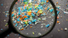 Colorful microplastics under a magnifying glass on a dark surface