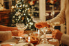 A holiday dinner party toasting with champagne coupes in front of a lit tree