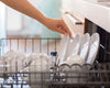 Loading a dishwasher with plates, bowls, and mugs