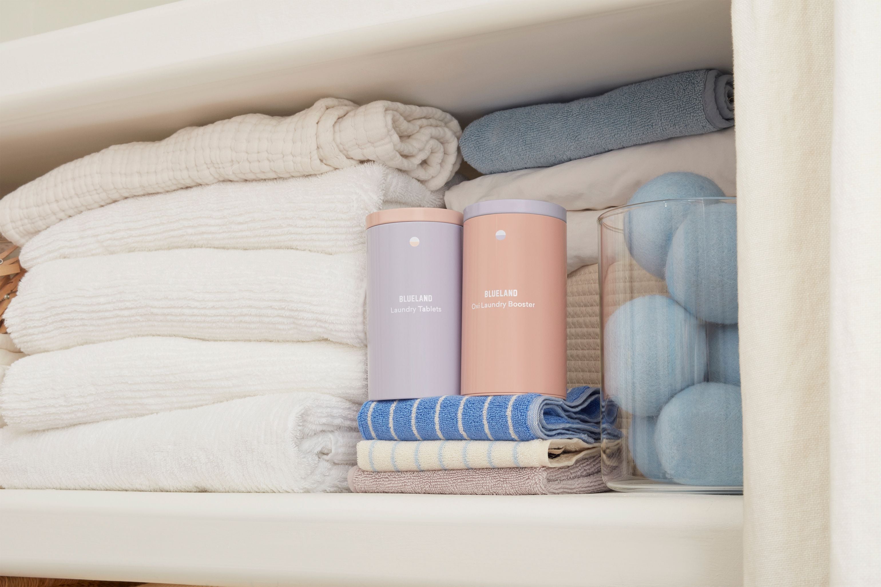 Folded clothes and cylindrical containers labeled 'Blueland' in a drawer.