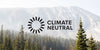 The Climate Neutral Logo over forest trees and a mountain