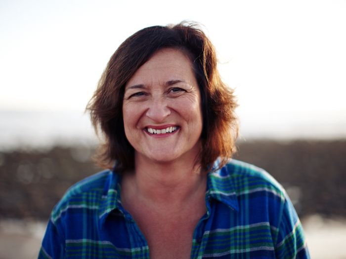 Woman wearing a blue plaid shirt with a blurred natural background
