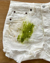 White shorts with a large dark grass and dirt stain