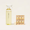 A Multi-Surface Cleaner refillable spray bottle, six small brown packets, and three tablets. Made with plant-based ingredients, these packets are ideal for eco-friendly cleaning.